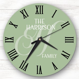 May include: A green round clock with black Roman numeral hour markers and black hands. The clock face has a white monogram "H" and the text "The Harrison Family".