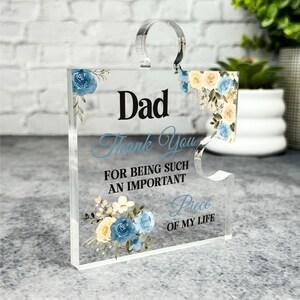 Può includere: Un pezzo di puzzle in acrilico trasparente con un motivo floreale e il testo "Dad Thank You for being such an important Piece of my life".