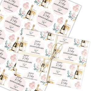 Könnte beinhalten: Geschenkpapier mit einem sich wiederholenden Muster aus Champagnerflaschen, Gläsern, rosa Ballons und floralen Akzenten. Das Design enthält Kreise mit dem Text "Happy Ruby Anniversary" und den Namen "Sophia & William".