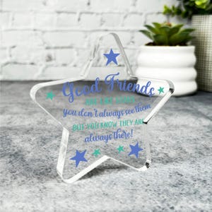 Puede incluir: Un pisapapeles de estrella de acrílico transparente con el texto "Good Friends are like stars you don't always see them but you know they are always there!" en letras azules y verdes.