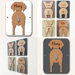 Op de afbeelding: Set van zes haken in de vorm van een hondenkont met de namen "Henry", "Cookie", "Sandy", "Elvis", "Rolo" erop gegraveerd. De haken zijn gemaakt van hout en zijn verkrijgbaar in verschillende kleuren, waaronder wit, grijs, bruin en groen.