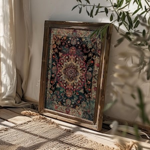 Puede incluir: Una alfombra enmarcada de estilo vintage con un patrón floral colorido en tonos rojos, azules y verdes. La alfombra está colgada en una pared blanca con un suelo de madera y una cortina beige en el fondo.