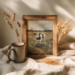 Cow printable artwork in rustic wooden frame, placed on linen fabric with ceramic mug and dried grass, soft farmhouse aesthetic