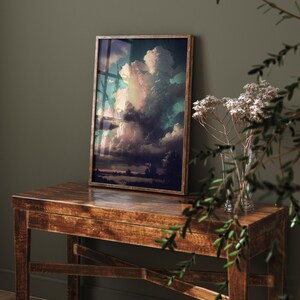 May include: A framed print of a colorful landscape painting with a large, dramatic cloud formation in the sky. The painting is in a dark wood frame and is hanging on a wall.