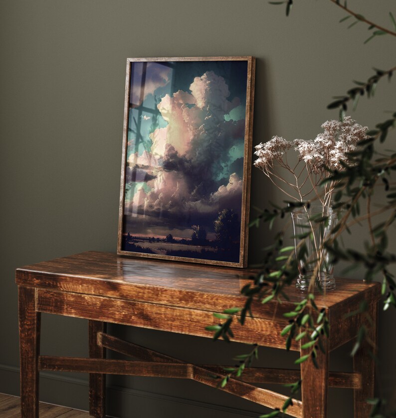 May include: A framed print of a colorful landscape painting with a large, dramatic cloud formation in the sky. The painting is in a dark wood frame and is hanging on a wall.