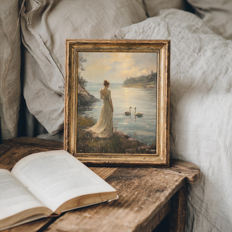 A graceful depiction of nature with a lady near a lake at sunset. This moody swan themed print enhances light academia, farmhouse, or cottagecore interiors.