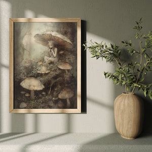 May include: A framed illustration of a fairy sitting under a mushroom in a forest setting. The fairy is wearing a white dress and has long, flowing hair. The mushrooms are brown and white and are surrounded by green foliage.