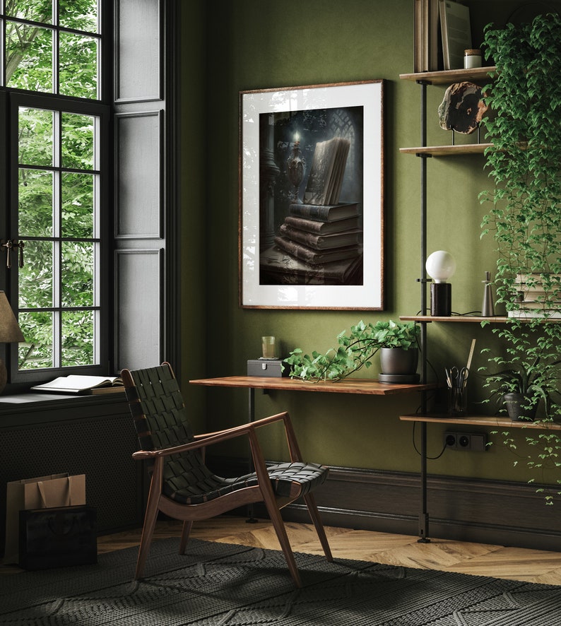 May include: A framed print of a still life featuring a stack of old books, a candle, and a window with light shining through. The print is hanging on a green wall in a home office with a desk, chair, and plants.