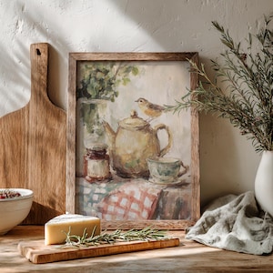 Puede incluir: Pintura enmarcada que representa una naturaleza muerta con una tetera, una taza y un pajarito. La pintura tiene una estética vintage, con colores suaves y un mantel a cuadros. Una tabla de cortar de madera, queso y ramitas de romero están en primer plano.
