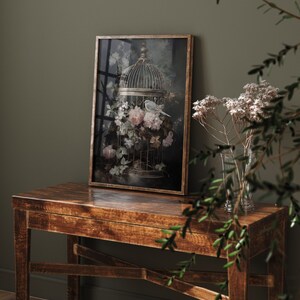 May include: A framed print of a bird in a cage surrounded by pink and white flowers. The cage is made of metal and has a delicate design. The background is a dark green color.
