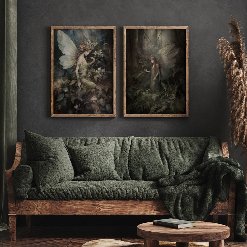 May include: Two framed art prints depicting ethereal fairies in a forest setting. The artwork features soft colors, with a focus on nature and fantasy themes. The frames are a warm wood tone, complementing the dark wall and green sofa.