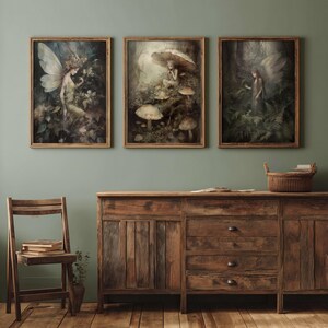 May include: Three framed art prints featuring fantasy scenes with fairies and mushrooms. The artwork has a vintage aesthetic with muted colors and detailed depictions of nature. The frames are made of light brown wood, and the overall theme is whimsical and enchanting.
