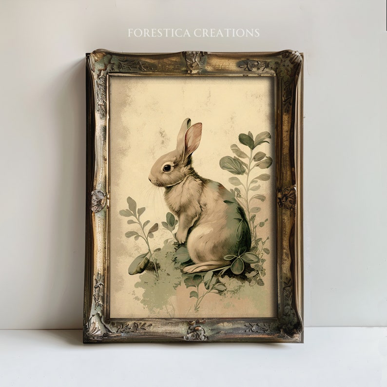 Pu&ograve; includere: Un'illustrazione vintage di un coniglio marrone seduto in un ciuffo di foglie verdi. L'immagine &egrave; incorniciata in una cornice dorata.