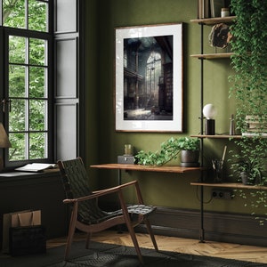 May include: A green wall with a framed black and white photograph of a grand staircase with a large window at the top. A wooden desk with a chair sits in front of the photograph. A shelf with plants and books is on the right side of the image.