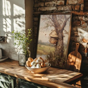 May include: A wooden table with a bowl of speckled brown eggs, a glass jar with green plants, and a framed painting of a tree with a birdhouse. The painting is on a brick wall.