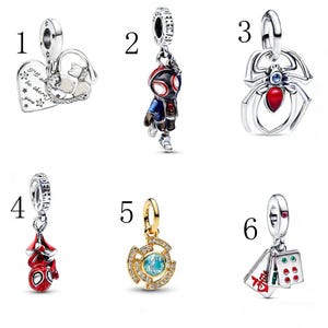 Puede incluir: Una colecci&oacute;n de seis colgantes de abalorios. Los abalorios incluyen un coraz&oacute;n con texto, una figura de Spider-Man, una ara&ntilde;a, un abalorio de Spider-Man, un abalorio dorado con una piedra azul y abalorios con dados y texto.