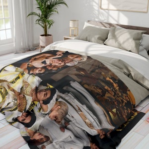 May include: A black and white blanket with a collage of images of people. The blanket features a yellow and black caution tape design with the text "PASTRY" printed on it.