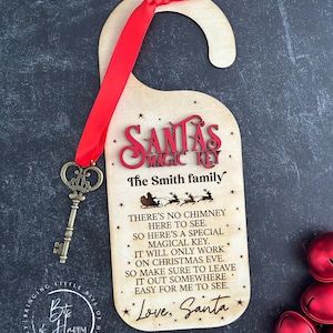 May include: A wooden door hanger with the text "Santa's Magic Key" in red, includes a decorative key and a red ribbon. The text on the hanger explains the key's purpose for Christmas Eve. The family name is also included.