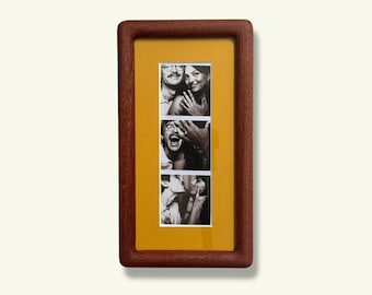 May include: A wooden framed photo display with three black and white images. The frame is a dark brown color, and the matting is yellow. The photos appear to be of people in various poses.