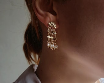 Puede incluir: Pendientes de oro con un diseño tejido y una cadena de pequeñas perlas que cuelgan de la parte inferior.