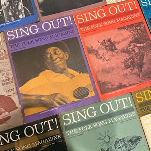 Könnte beinhalten: Eine Sammlung von Vintage-Magazinen "Sing Out!" mit Volksliedern. Die Cover zeigen Porträts, Illustrationen und Text. Farben sind Rot, Lila, Grün und Gelb. Die Zeitschriften stammen aus den 1960er und 1980er Jahren.