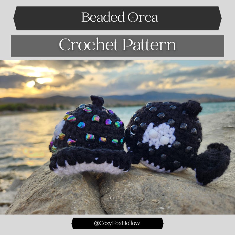 K&ouml;nnte beinhalten: Zwei geh&auml;kelte Orca-Figuren, eine aufrecht und eine auf der Seite, mit schwarzem und wei&szlig;em Garn und schillernden Perlen. Der Text "Beaded Orca Crochet Pattern" steht oben. Die Figuren befinden sich auf einem Felsen mit malerischem Hintergrund.