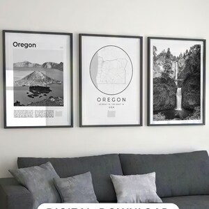 May include: Three black framed prints of Oregon landscapes. The left print shows a black and white photo of a volcanic island in a lake. The middle print shows a black and white map of Oregon with the text "OREGON 45.8041° N, 120.5542° W USA". The right print shows a black and white photo of a waterfall in a forest.