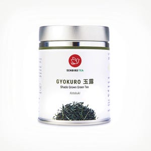May include: A cylindrical metal container of Gyokuro shade-grown green tea. The label features the text "SENBIRD TEA" and "GYOKURO" in both English and Japanese. A red logo is above the text. The bottom of the container shows a pile of green tea leaves.
