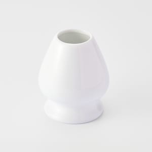 May include: A white ceramic matcha whisk holder with a rounded base and a wide opening at the top.