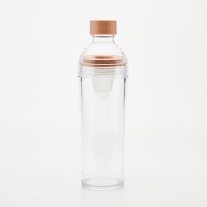 Puede incluir: Una botella de agua de plástico transparente con una tapa marrón y un colador integrado. La botella está diseñada para hacer agua infundida.