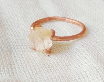 May include: A delicate ring with a clear quartz crystal set in a rose gold band.
