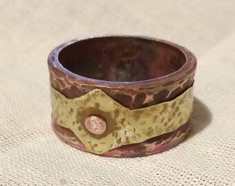 Puede incluir: Un anillo de cobre martillado con una banda de latón y un acento de cobre. El anillo tiene un acabado texturizado.