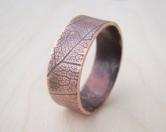 Puede incluir: Brazalete de puño color cobre con un patrón de venas de hojas. El brazalete tiene forma rectangular con bordes redondeados. El patrón de hojas está grabado en el metal, creando una superficie detallada y texturizada. Una joya única.