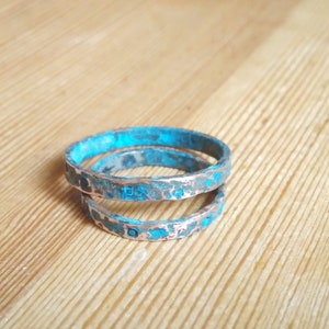 May include: Two turquoise and silver rings stacked on top of each other. The rings are textured and have a distressed look.
