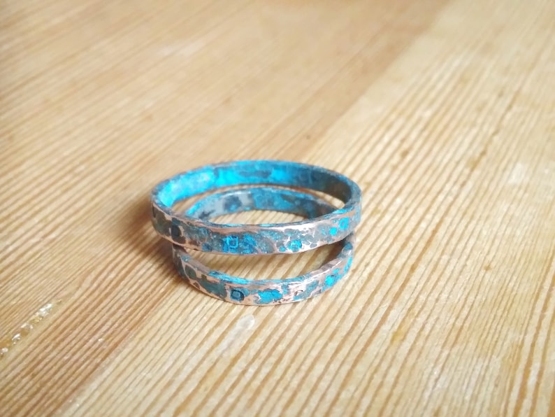 May include: Two turquoise and silver rings stacked on top of each other. The rings are textured and have a distressed look.