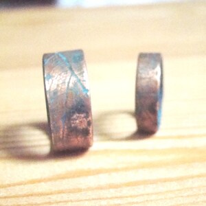 May include: Two copper rings with a textured surface and a blue patina. The rings are different sizes.