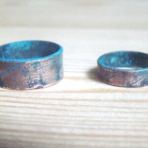 May include: Two copper rings with a blue patina finish. The rings have a textured surface that resembles a leaf pattern.