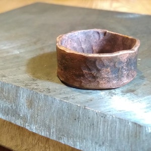 May include: A hammered copper ring with a rustic finish. The ring is thick and has a wide band.