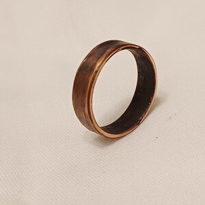 May include: A simple copper band ring with a slightly hammered finish. The ring is a warm, reddish-brown color.
