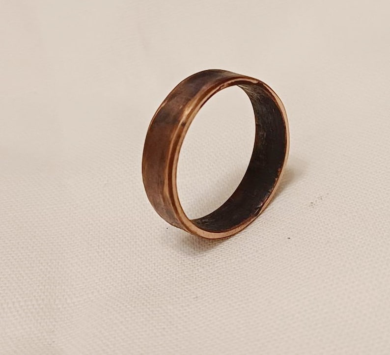 May include: A simple copper band ring with a slightly hammered finish. The ring is a warm, reddish-brown color.