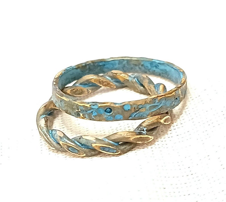 May include: Two intertwined rings, one with a twisted design and the other with a textured surface, both with a blue and gold finish.