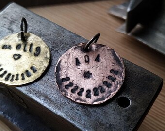 May include: Two round metal tags with black lettering. The tag on the left is brass and says "Mr. Olly Ramirez" with a heart symbol. The tag on the right is copper and says "404" with a star symbol and a circle of numbers.