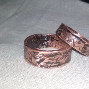 Puede incluir: Dos anillos de cobre con un acabado texturizado y martillado. Los anillos est&aacute;n apilados uno encima del otro.
