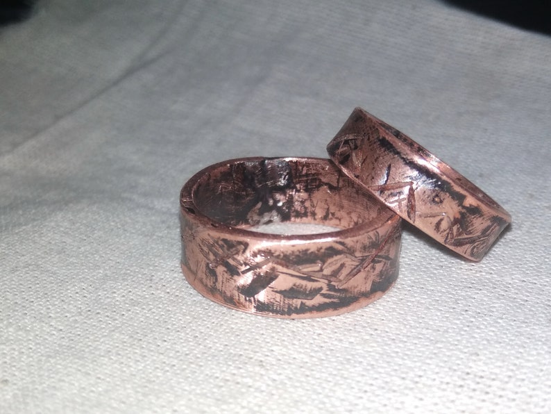 Puede incluir: Dos anillos de cobre con un acabado texturizado y martillado. Los anillos est&aacute;n apilados uno encima del otro.