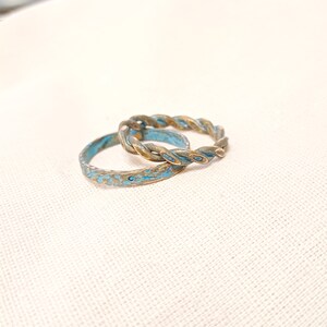 May include: Two rings, one with a twisted design and the other with a textured surface, both with a blue and gold finish.