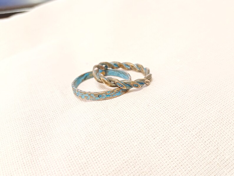 May include: Two rings, one with a twisted design and the other with a textured surface, both with a blue and gold finish.