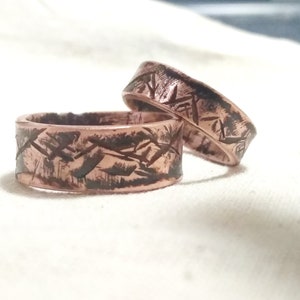 Puede incluir: Dos anillos de cobre con un acabado texturizado y martillado. Los anillos est&aacute;n apilados uno encima del otro.