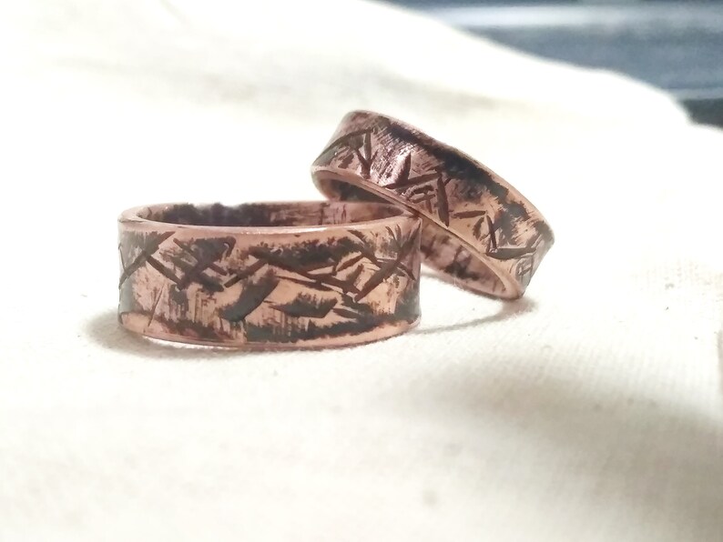 Puede incluir: Dos anillos de cobre con un acabado texturizado y martillado. Los anillos est&aacute;n apilados uno encima del otro.