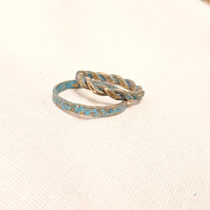 May include: Two turquoise and gold rings, one with a twisted design and the other with a textured surface.