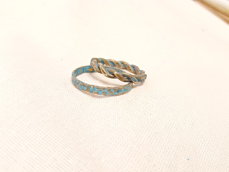 May include: Two turquoise and gold rings, one with a twisted design and the other with a textured surface.